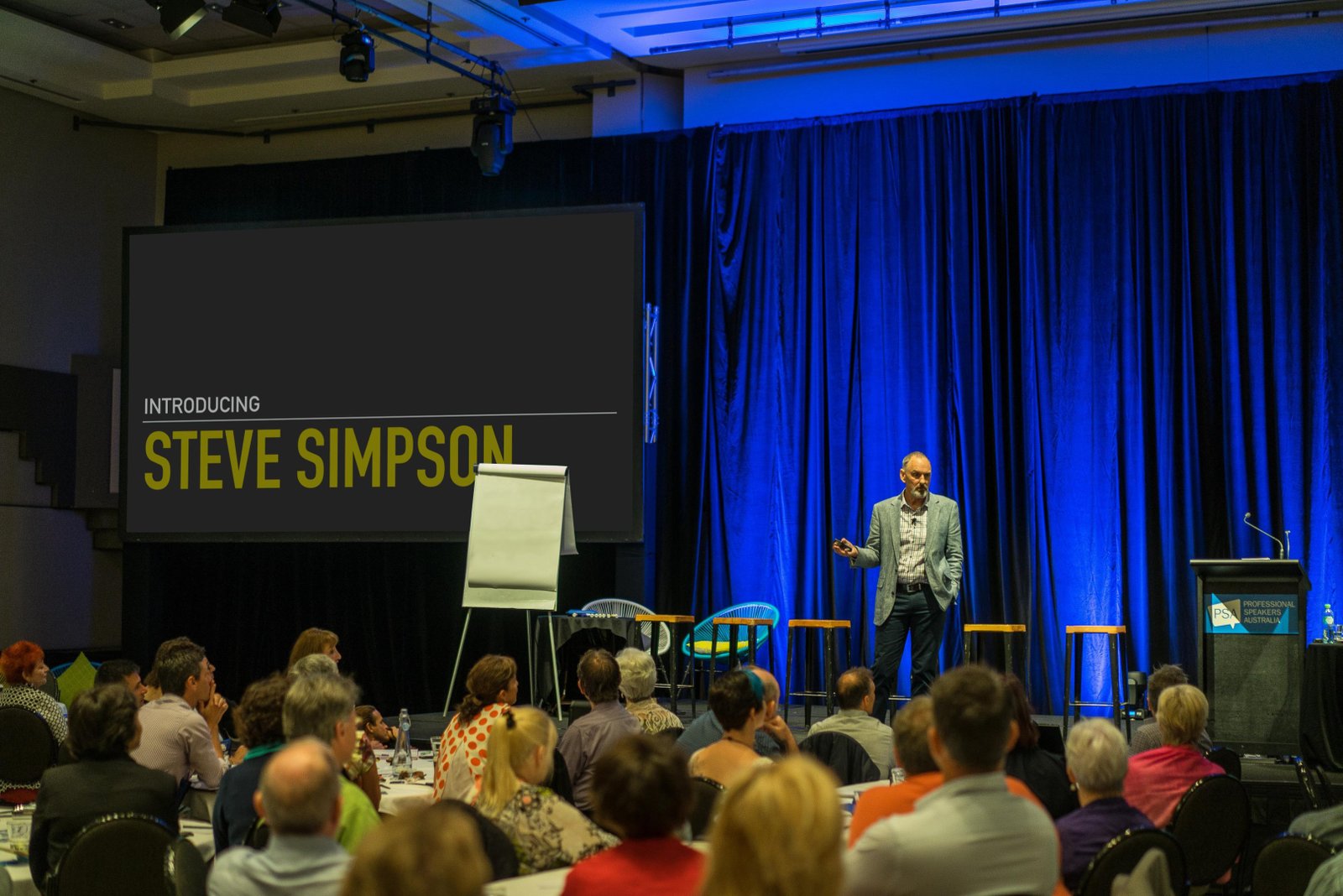 Steve Simpson speaking on a large conference stage