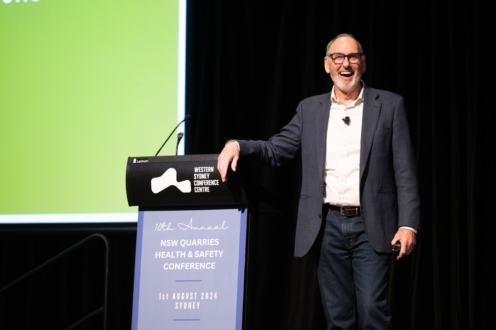 Steve Simpson smiling on stage at the NSW Quarries Health and Safety Conference