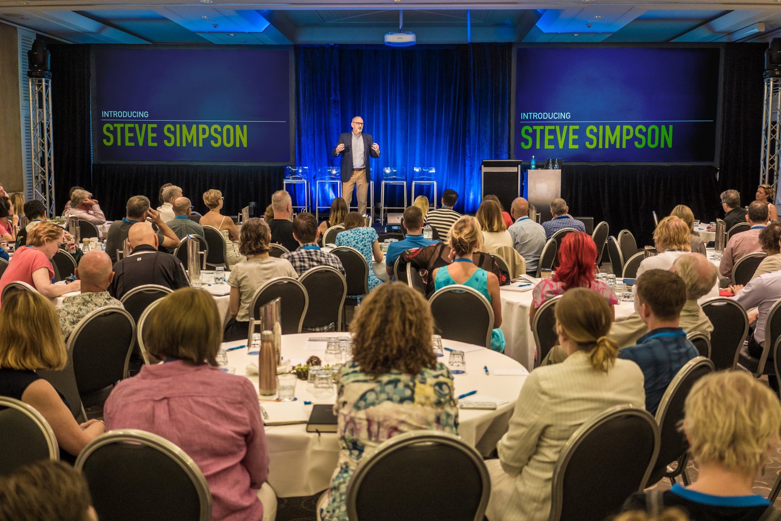 Wide view of Steve Simpson presenting to a conference audience